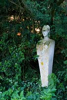 Statue en pierre parmi les conifères Taxus - If - et Ilex - Holly