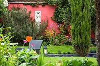 Vue sur la pelouse de parterre de fleurs colorées contre le mur rose