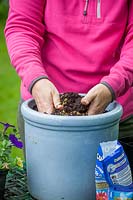 Planter un pot de plantes annuelles, en mélangeant de l'engrais à libération lente