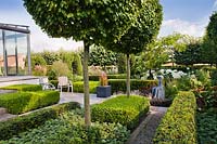 Vue sur le jardin moderne, avec des haies basses et des ifs, Carpinus betulus - Normes topiaires des sucettes charme et un espace de détente.
