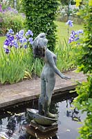 Étang rectangulaire avec fontaine sculpture d'une jeune fille se lavant les cheveux, parterre de fleurs Iris derrière