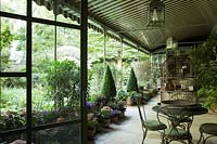 Deux vérandas ombragées relient l'espace extérieur dominé par des pots de fleurs violettes préférés de Pierre Berge