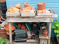 Pots en terre cuite et pots en plastique stockés à l'extérieur sous l'ancien banc.