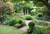 Jardin de la petite ville ombragée avec Buxus - Boîte - topiaire, plantation de parterres de fleurs et pavillon d'été