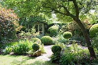 Jardin de la petite ville ombragée avec Buxus - Boîte - topiaire, parterres de fleurs mixtes et un pavillon d'été