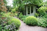 Jardin de la petite ville ombragée avec parterres de fleurs mixtes avec Buxus - Box - topiaire près de chemin de gravier à la maison d'été