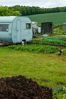 Vieilles caravanes et hangars utilisés pour le stockage sur les attributions du village avec la campagne ouverte au-delà - Open Gardens Day, Yoxford, Suffolk
