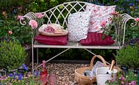Banc de jardin en métal avec coussins pour la détente dans un jardin abrité - RHS Chelsea Flower Show.