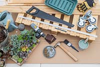 Outils et matériaux pour créer une table de palette de plantes succulentes sur roulettes.