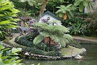 Maison de canard décorative près de l'eau dans un jardin tropical