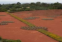 Vue d'ensemble du jardin de sable rouge imitant l'intérieur rouge de l'Australie, avec des parterres de Chrysocephalum apiculatum et Westringia fruticosa - Romarin côtier - avec des arbres et des paysages au-delà