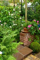Entrée de jardin potager à travers l'arche métallique soutenant les roses grimpantes, avec fougère, fort et rosier de chaque côté du chemin - Journée des jardins ouverts, Double Street, Framlingham, Suffolk
