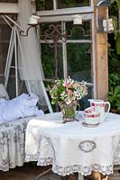 Table basse avec vaisselle vintage dans la salle de jardin avec chaise balançoire