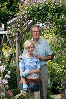 Couple dans leur jardin par grimpeur en fleurs sur un support rustique