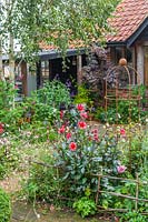Clôture rustique bordant les parterres et obélisque en acier cor-ten avec vue sur jardin studio