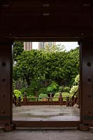 Vue à travers une porte de la passerelle couverte autour de la cour de l'étang de lotus, à un petit jardin latéral