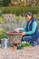Femme ajoutant des pots au fond du pot pour empêcher le compost de s'écouler à travers les trous de drainage
