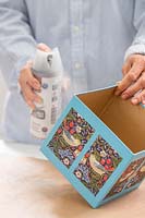 Femme appliquant un scellant transparent à base de spray à l'extérieur de la boîte en carton