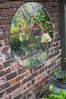 Sur une paroi latérale, un miroir en forme de dôme reflète des images déformées de fleurs dans le parterre central.