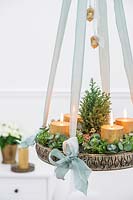 Arrangement de l'Avent suspendu avec bougies en or, sapin de Noël miniature et feuillage d'eucalyptus et de Hebe