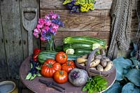Légumes d'été dans un cadre rustique. Courgettes, tomates boeuf, menthe, haricots verts grimpants, pommes de terre Inca Gold, statice, pois de senteur, betterave Boltardy.
