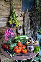 Légumes d'été dans un cadre rustique, notamment courgette, steak, tomate, menthe, haricots verts grimpants, pommes de terre Inca Gold, statice, pois de senteur et betterave Boltardy.