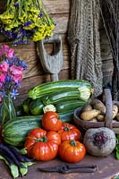 Légumes d'été dans un cadre rustique, notamment courgette, steak, tomate, menthe, haricots verts grimpants, pommes de terre Inca Gold, statice, pois de senteur et betterave Boltardy.