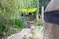 Cailloux décoratifs de chaque côté du chemin de gravier, avec surplomb Salix - Willow. École primaire Sedlescombe, Sussex, Royaume-Uni.
