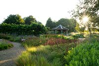 Astilbe chinensis tacqetii 'Purplelanze' et herbes autour d'un pavillon au lever du soleil dans le jardin du millénaire au parc naturel de Pensthorpe