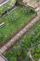 Vue aérienne du jardin avec des bordures de légumes à fleurs et des arbres fruitiers formés sur arcade reliée par des chemins de brique et de pierre - Hollande, juin