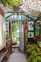 Salle de jardin à l'ancienne, ou hangar de rempotage, rempli de matériel de jardinage vintage et de paraphanales, portes et fenêtres victoriennes en vitrail recyclé