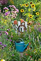 Arrosoir par clôture de jardin dans un potager coloré.