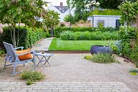 Un jardin de ville contemporain avec coin salon gravillonné, pelouse surélevée, parterre de fleurs sauvages et jardin au toit vert.