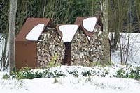 Maisons de stockage en métal rouillé avec du bois dans la neige.