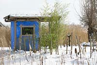 Maison de jardin bleu conçue par Meneer Vermeer au milieu de la neige.