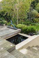 Jardin de ville à faible entretien - vue depuis une terrasse en bois surélevée avec piscine réfléchissante