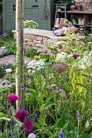 Vue à travers le parterre de fleurs naturaliste, y compris Daucus carota et Ammi majus en regardant vers le siège en pierre sèche. Le jardin Naturecraft - Festival des fleurs de Hampton Court 2019