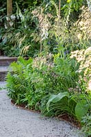 Vue le long du chemin compacté avec bordure en acier vers des marches avec parterres de fleurs naturalistes. Jardin Stop and Pause, Festival des fleurs de Hampton Court, 2019.