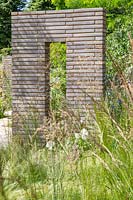 Jardin avec graminées ornementales divisé par des colonnes et des murs de pavés en brique de Belgique. Jardin du sanctuaire RHS - Festival des fleurs de Hampton Court 2019