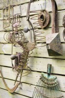Outils de jardin rouillés affichés sur une clôture dans un jardin de cottage