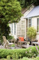 Studio de jardin d'architecte avec coin salon extérieur encadré de haies et de lierre taillé dans un jardin de cottage en juin