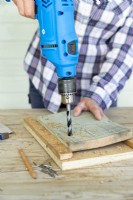 Femme perçant un trou dans une planche de bois