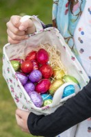 Petite fille participant à une chasse aux œufs de Pâques dans un jardin