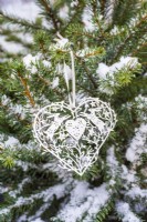 Coeur en filigrane de papier blanc sur l'arbre de Noël enneigé