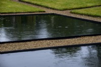 Piscine réfléchissante noire entourée de gravier dans le jardin à l'italienne à Thenford Arboretum