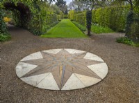 Boussole en pierre décorative pavée sur une surface de gravier. Jardins de l'ancien presbytère East Ruston Norfolk