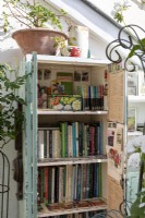 Bibliothèque de véranda remplie de livres de jardiniers, de pots et d'accessoires de jardinage