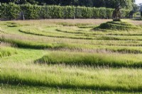 Labyrinthe d'herbe avec un monticule en spirale en son centre surmonté d'une poire faite d'outils de jardin rouillés au Gordon Castle Walled Garden, en Écosse en juillet