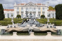 Fontaine ornée dans un étang surélevé montrant la sculpture, au-delà du parterre et du palais. Queluz, Lisbonne, Portugal, septembre.