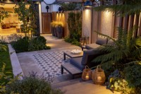 Jardin contemporain de nuit avec patio, regardant vers la maison et la cuisine